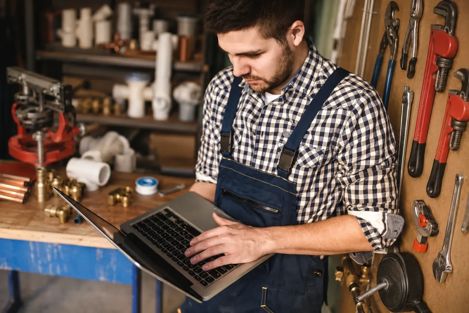 A plumber in his workshop checking his business on a laptop